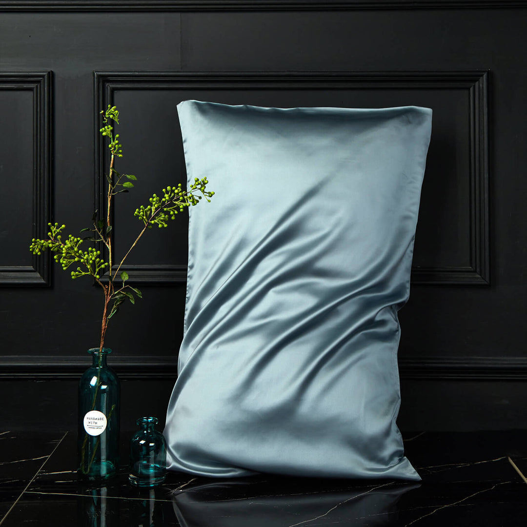 Blue-gray silk pillowcase displayed upright against a dark background