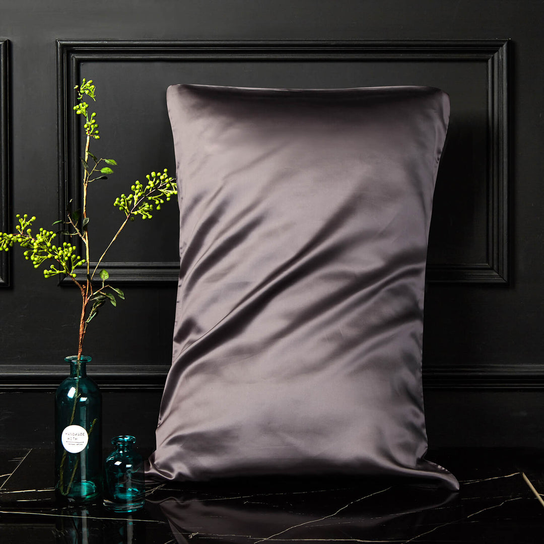 Dark gray silk pillowcase displayed upright against a dark background