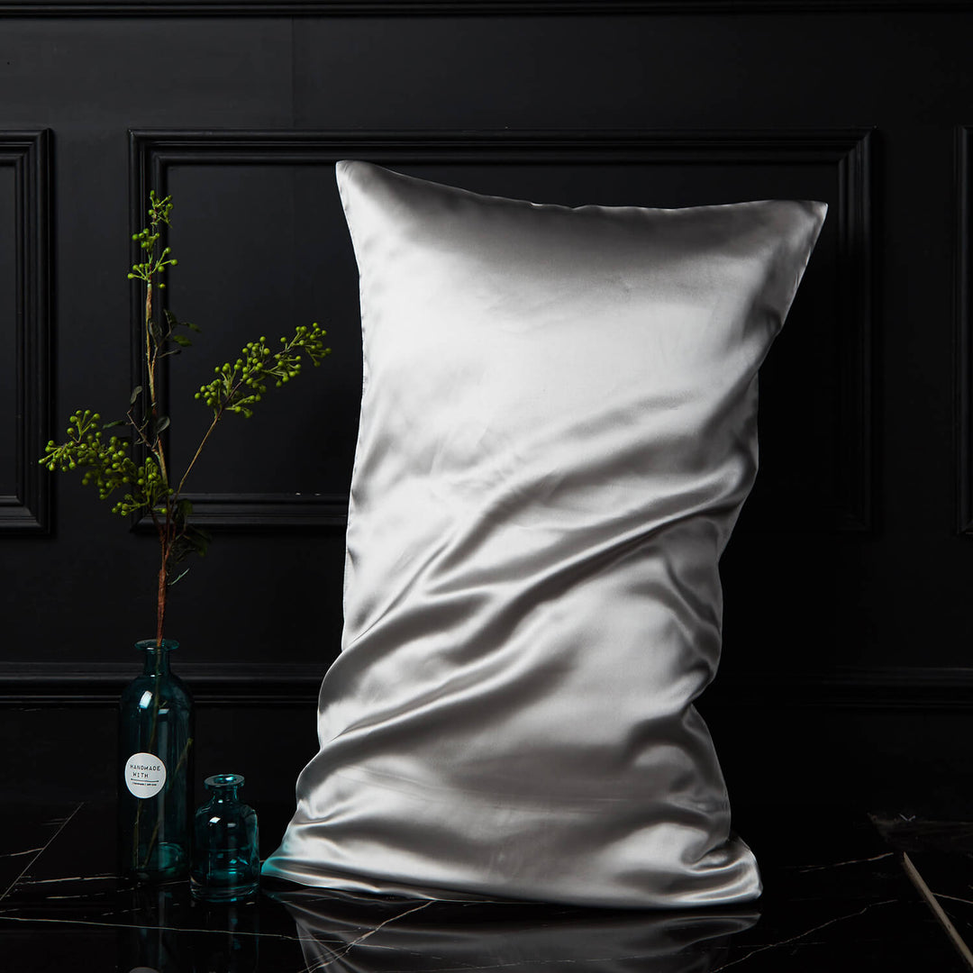Light silver silk pillowcase displayed upright against a dark background