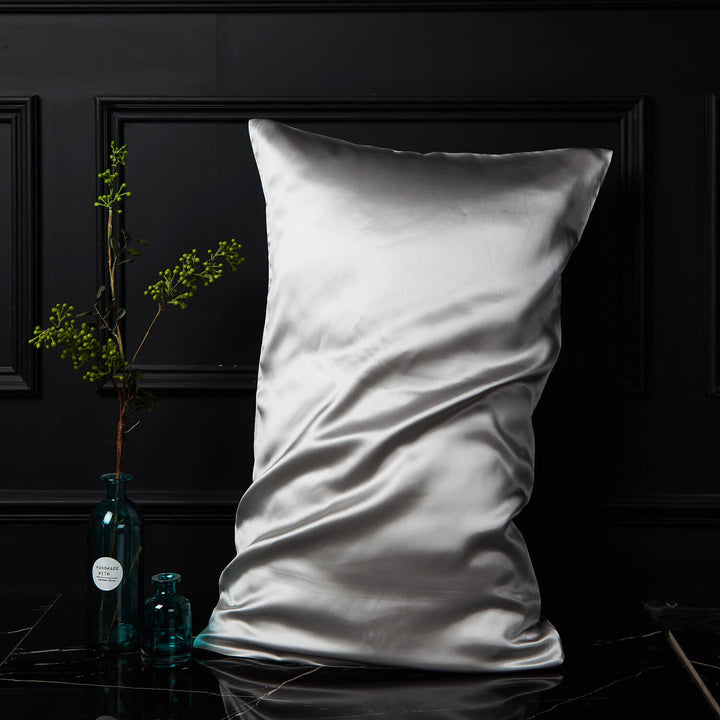 Light silver silk pillowcase displayed upright against a dark background