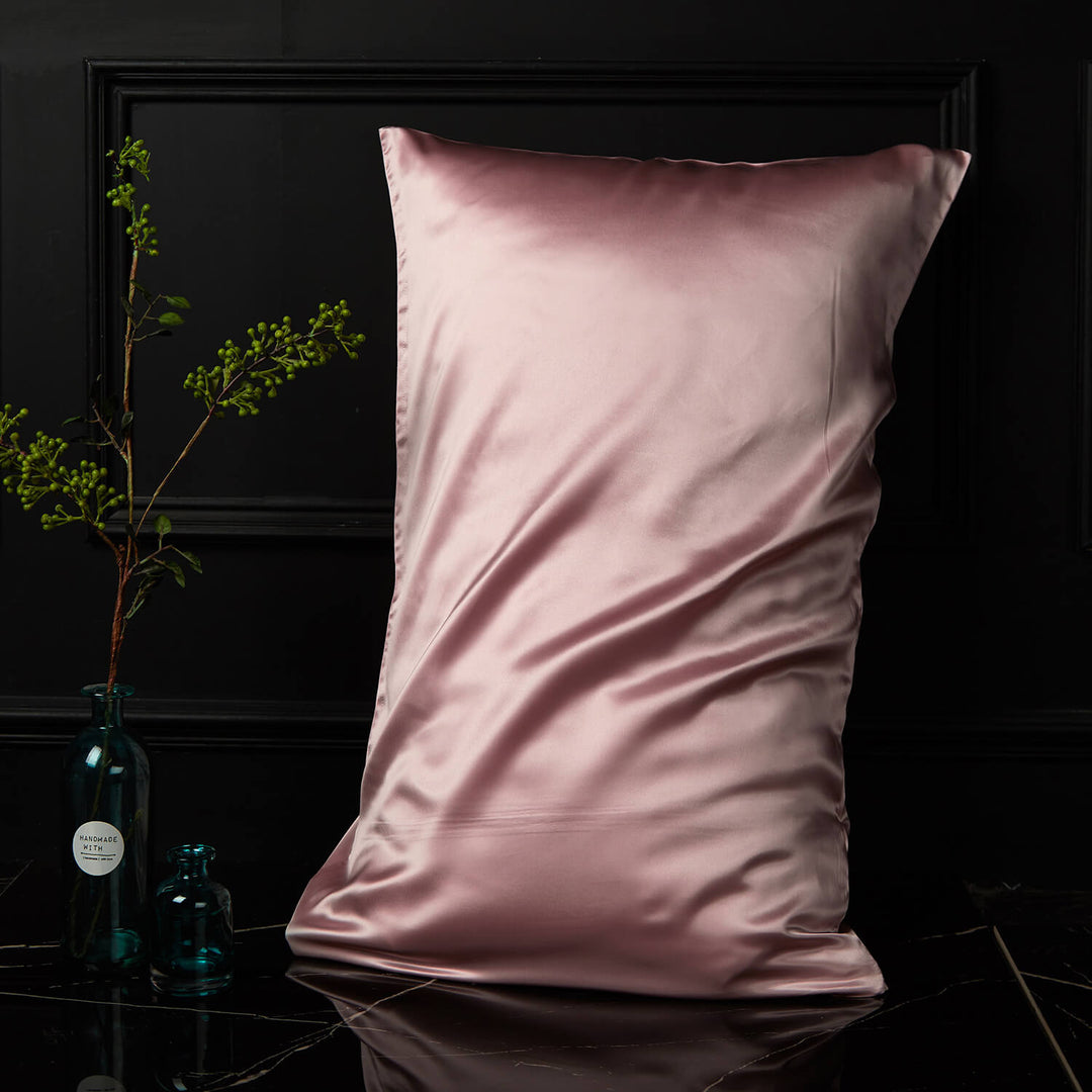 Pink silk pillowcase displayed upright against a dark background