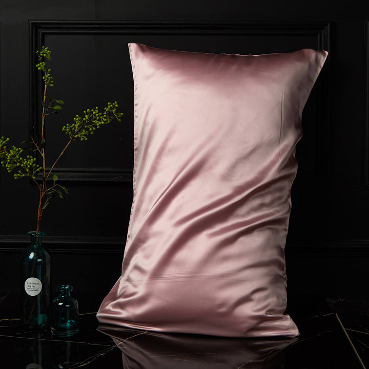 Pink silk pillowcase displayed upright against a dark background