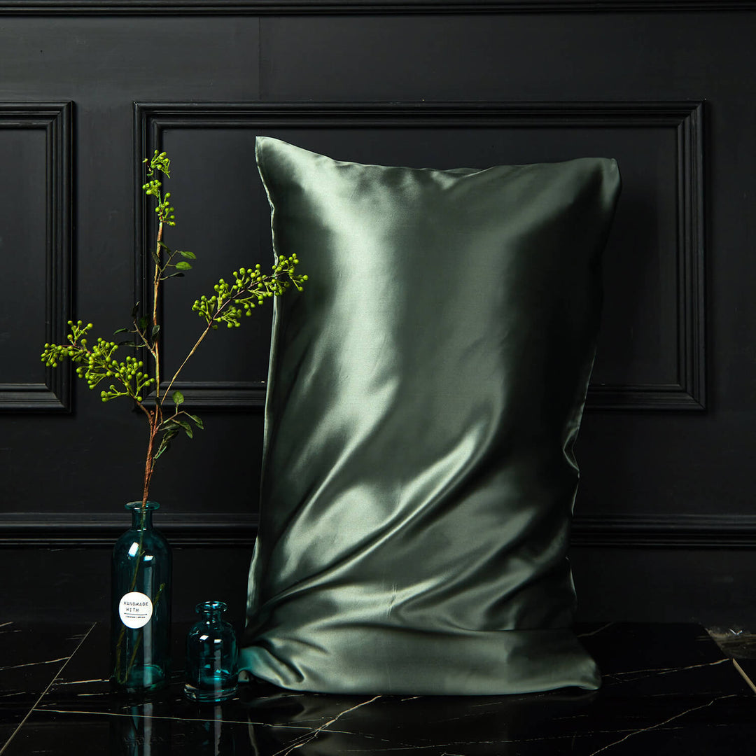 Dark green silk pillowcase displayed upright against a dark background