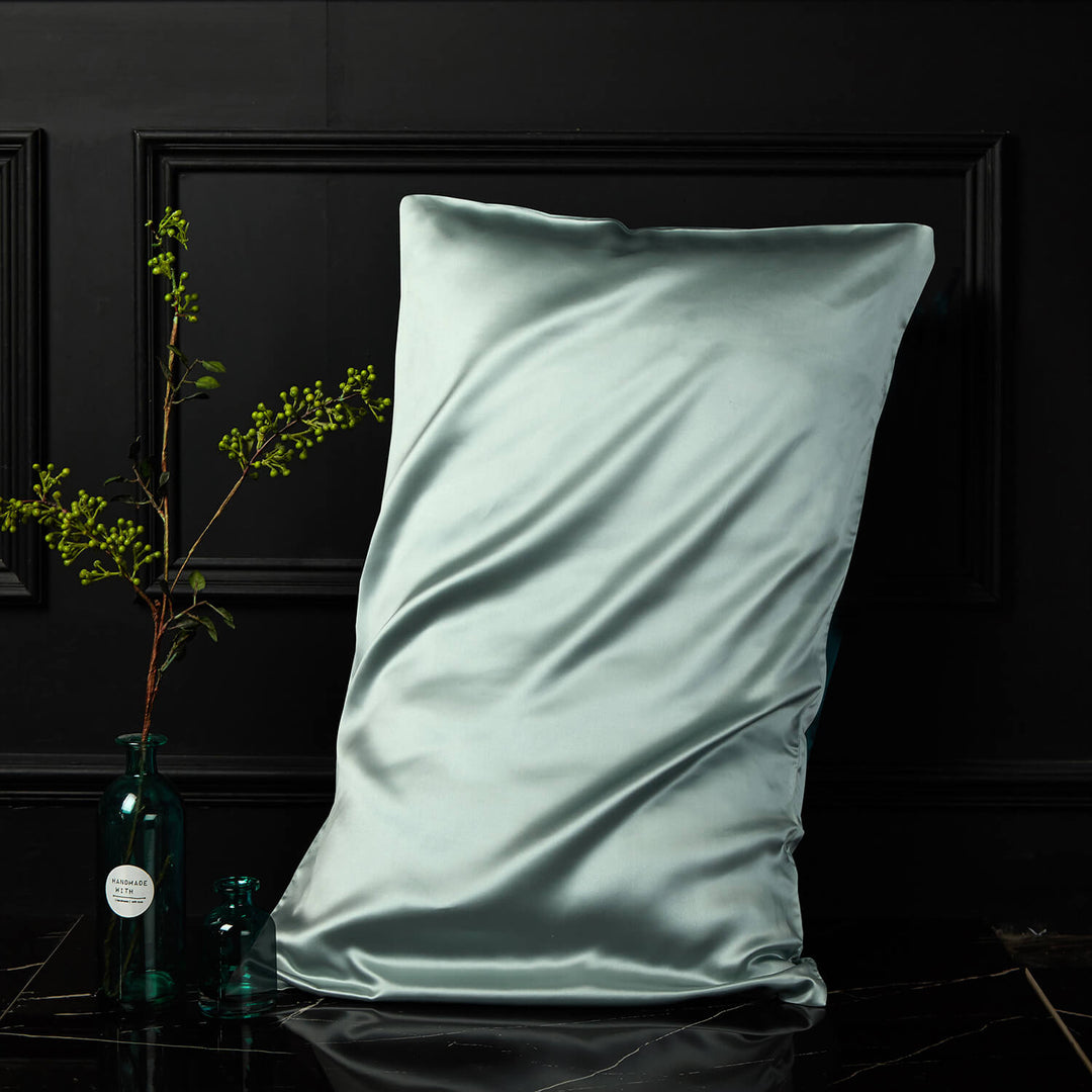 Mint green silk pillowcase displayed upright against a dark background