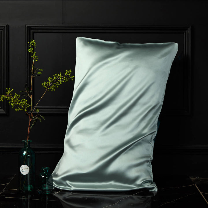 Mint green silk pillowcase displayed upright against a dark background