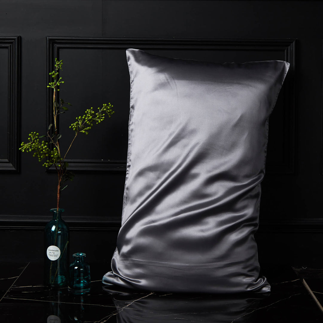 Silver-gray silk pillowcase displayed upright against a dark background