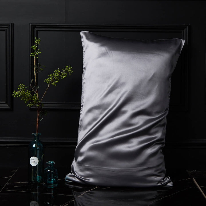 Silver-gray silk pillowcase displayed upright against a dark background