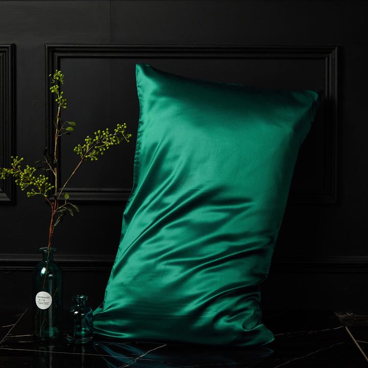 Emerald green silk pillowcase displayed upright against a dark background